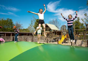 Kinderen spelen op een springkussen bij een Safari Trekking tent op Camping 't Geuldal in Nederland.
