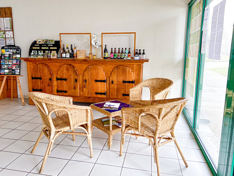 Bright reception area with wicker chairs, brochures, and regional drinks displayed on a wooden sideboard.
