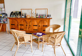 Bright reception area with wicker chairs, brochures, and regional drinks displayed on a wooden sideboard.