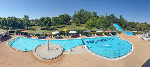 Buitenbad met ligstoelen, parasols en waterglijbaan bij Onlycamp Camping le Champ d’Eté, Frankrijk.