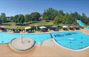 Outdoor swimming pool with lounge chairs, umbrellas, and waterslide at Onlycamp Camping le Champ d’Eté, France.