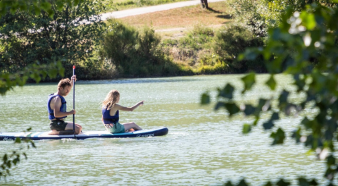 Zwei Personen paddeln auf einem Board auf dem See bei Onlycamp Camping Le Lac de Roybon in Frankreich.
