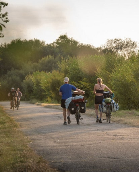Deux personnes marchent avec leurs vélos chargés près de Roybon, France, alors que deux cyclistes arrivent en sens inverse.