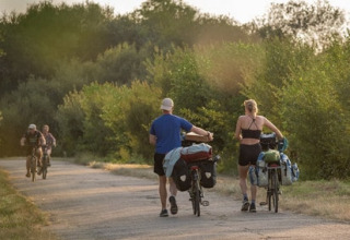 Deux personnes marchent avec leurs vélos chargés près de Roybon, France, alors que deux cyclistes arrivent en sens inverse.
