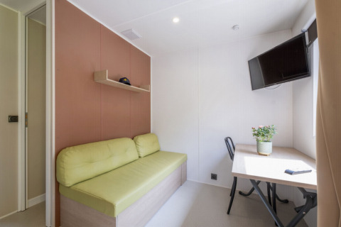 Modern interior of a Static caravan Comfort at Seasonova Camping Le Plan d’Eau, France, featuring sofa and desk.