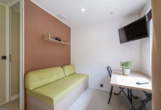 Interno moderno di una Static caravan Comfort a Seasonova Camping Le Plan d’Eau, Francia, con divano e scrivania.
