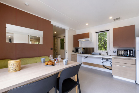 Modern kitchen and dining area in Mobile home Comfort MIVA at Seasonova Camping Le Plan d’Eau, France.
