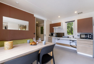 Modern kitchen and dining area in Mobile home Comfort MIVA at Seasonova Camping Le Plan d’Eau, France.
