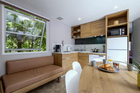 Modern kitchen and dining area in Mobile home Confort at Seasonova Camping Le Plan d’Eau, France, with wooden décor.