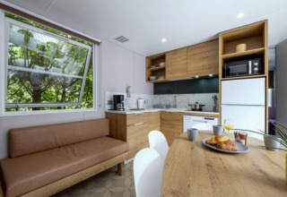Modern kitchen and dining area in Mobile home Confort at Seasonova Camping Le Plan d’Eau, France, with wooden décor.