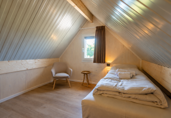Chambre mansardée lumineuse à Duinlodge 4, EuroParcs Cadzand-Bad, avec lit simple et fauteuil confortable.