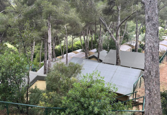 Zicht op Villatent Compact safaritenten bij Camping Rosselba Le Palme in Italië, tussen hoge bomen.