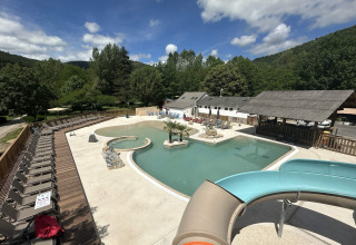 Buitenzwembad met waterglijbaan en ligzetels bij Flower Camping Le Pont du Tarn in Occitanië, Frankrijk.