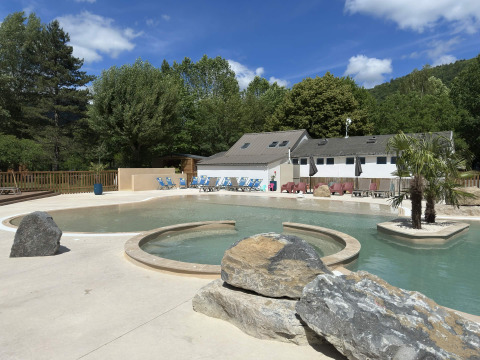 Außenpool und Ferienhaus im Flower Camping Le Pont du Tarn in Okzitanien, Frankreich an einem sonnigen Tag.