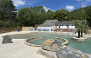 Udendørs swimmingpool og feriebolig ved Flower Camping Le Pont du Tarn i Occitanie, Frankrig på en solrig dag.