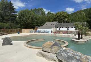 Udendørs swimmingpool og feriebolig ved Flower Camping Le Pont du Tarn i Occitanie, Frankrig på en solrig dag.