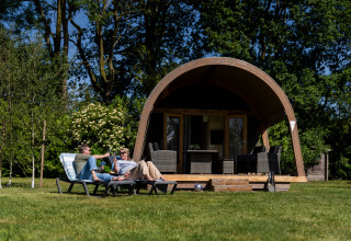 Zwei Personen entspannen auf Liegestühlen vor einem Safarizelt im Holiday center 't Schuttenbelt in den Niederlanden.