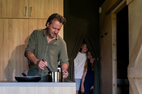 Man kookt in de keuken van safaritent Tent lodge XL + sanitair op Vakantiecentrum 't Schuttenbelt.