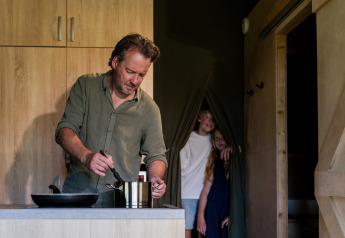 Uomo cucina nella cucina della tenda safari Tent lodge XL + servizi al centro vacanze 't Schuttenbelt.