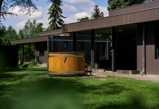 Boslodge Plus mit Hot Tub im Ferienpark 't Schuttenbelt, Niederlande. Holzlodge und gepflegter Garten.
