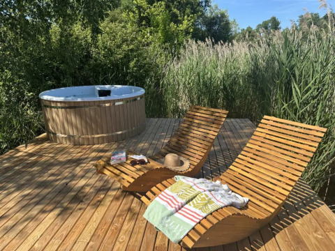 Terrazza in legno con lettini e vasca idromassaggio nella natura alla Cabane Spa «Loggy» in Francia.