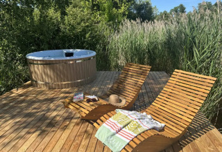 Terrazza in legno con lettini e vasca idromassaggio nella natura alla Cabane Spa «Loggy» in Francia.