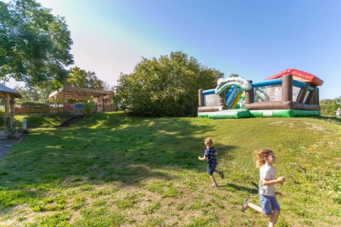 Zwei Kinder spielen draußen neben einer Hüpfburg im Seasonova Camping Le Brabois in Grand Est, Frankreich.