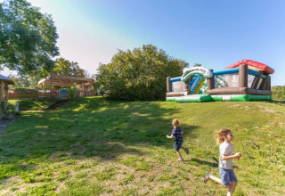 Deux enfants courent près d’un jeu gonflable au Seasonova Camping Le Brabois, à Grand Est, France.