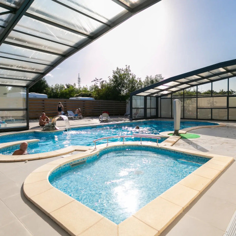 Piscine couverte avec eau claire, vacanciers profitant du soleil au Seasonova Camping Le Brabois, Grand Est, France.