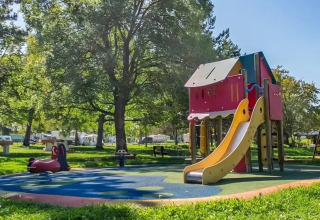 Spielplatz mit Rutsche im Seasonova Camping Le Brabois, Grand Est, Frankreich, an einem sonnigen Tag.