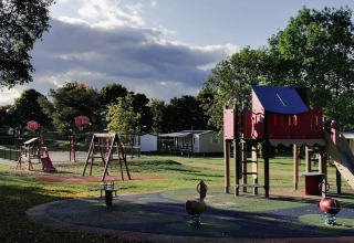 Spielplatz im Seasonova Camping Le Brabois, Grand Est, Frankreich, mit Rutschen, Schaukeln und Bäumen.