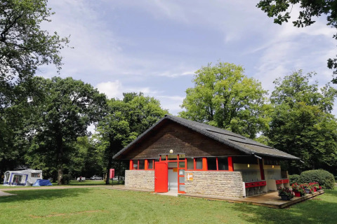 Gebäude im Ferienpark, umgeben von grünen Bäumen bei Seasonova Camping Le Brabois, Grand Est, Frankreich.