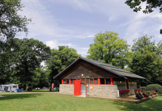 Gebäude im Ferienpark, umgeben von grünen Bäumen bei Seasonova Camping Le Brabois, Grand Est, Frankreich.