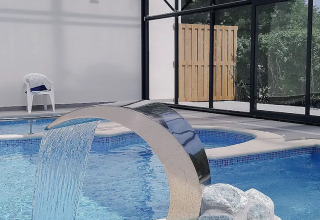 Piscine intérieure avec fontaine en cascade au camping Seasonova Le Brabois, dans le Grand Est, France.