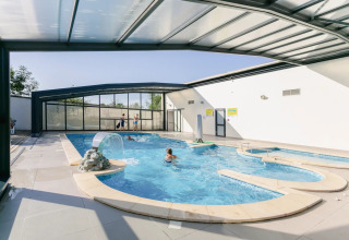 Innen- und Außenpool mit Glasdach im Seasonova Camping Le Brabois, Grand Est, Frankreich, mit Gästen.