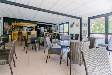 Heller, moderner Essbereich im Seasonova Camping Le Brabois, Grand Est, Frankreich, mit Flechtstühlen.