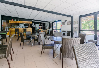Heller, moderner Essbereich im Seasonova Camping Le Brabois, Grand Est, Frankreich, mit Flechtstühlen.