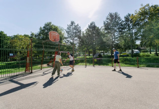 Des personnes jouent au basket sur un terrain extérieur ensoleillé au Seasonova Camping Le Brabois, Grand Est, France.