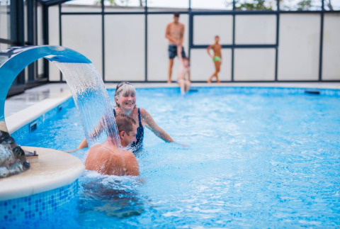 Famille profitant de la piscine intérieure avec cascade au Seasonova Camping Le Brabois, Grand Est, France.