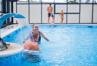 Famille profitant de la piscine intérieure avec cascade au Seasonova Camping Le Brabois, Grand Est, France.