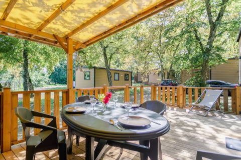 Terraza cubierta con mesa de comedor y tumbona en Seasonova Camping Le Brabois, Grand Est, Francia.