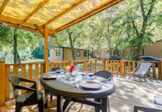 Terraza cubierta con mesa de comedor y tumbona en Seasonova Camping Le Brabois, Grand Est, Francia.