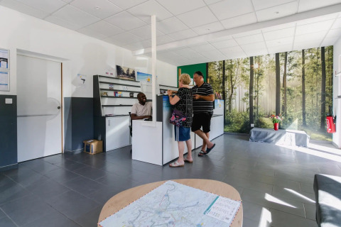 Accueil du Seasonova Camping Le Brabois, des clients discutant avec le personnel à Grand Est, France.