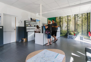 Empfangsbereich im Seasonova Camping Le Brabois mit Gästen und Personal im Gespräch, Grand Est, Frankreich.