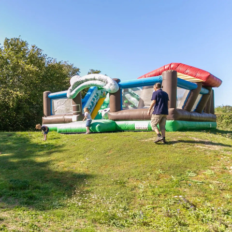 Kinder spielen auf einer aufblasbaren Hüpfburg bei sonnigem Wetter im Seasonova Camping Le Brabois, Grand Est