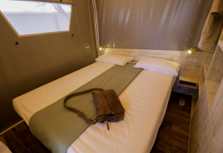 Vista interna di una tenda safari Maasaï Lodge al Seasonova Camping Le Brabois in Francia, con letto rifatto.