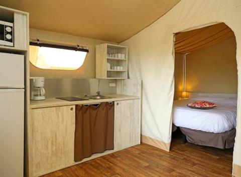 Vista interna della tenda safari Maasaï Lodge al Seasonova Camping Le Brabois, con angolo cottura e letto.