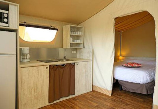 Vista interna della tenda safari Maasaï Lodge al Seasonova Camping Le Brabois, con angolo cottura e letto.