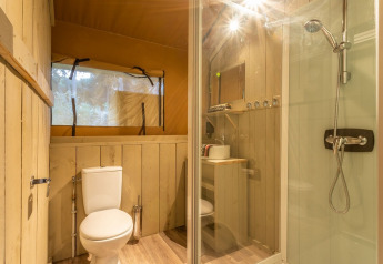 Badkamer met douche, toilet en houten accenten in een safaritent op Camping Luna del Monte, Italië.