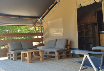 Buitenzitje bij Lodgetent safaritent op Camping Luna del Monte, Italië, met houten zitmeubels.
